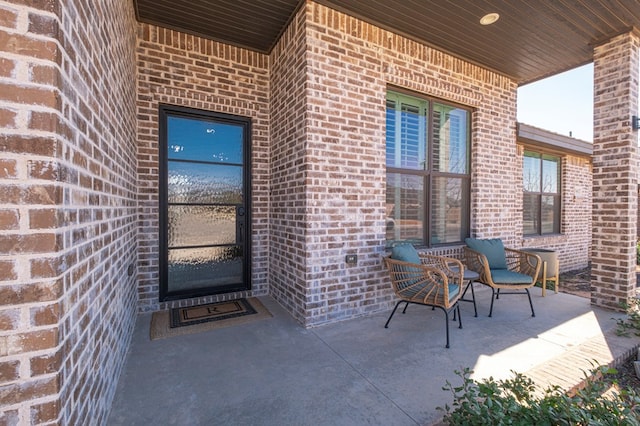 view of exterior entry with a porch and brick siding