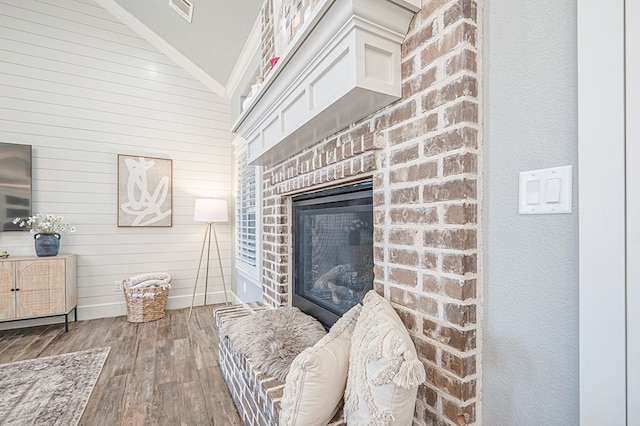 living room with a brick fireplace, dark wood finished floors, and wooden walls