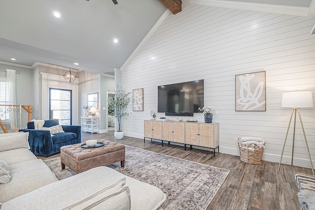 living room with baseboards, beamed ceiling, wood finished floors, crown molding, and high vaulted ceiling