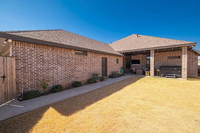 back of property featuring brick siding, a patio, a shingled roof, a lawn, and fence