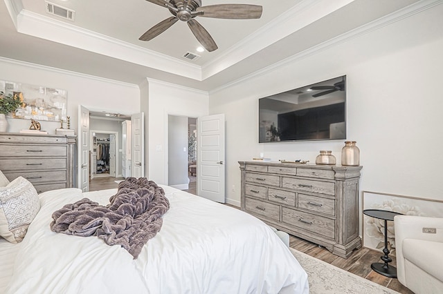 bedroom with light wood-type flooring, visible vents, and a tray ceiling