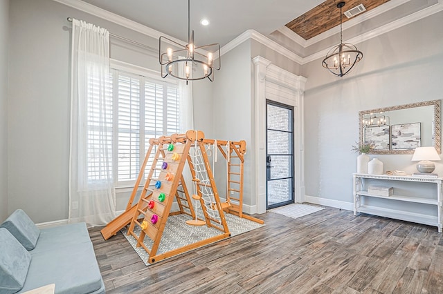 playroom featuring baseboards, visible vents, ornamental molding, wood finished floors, and a notable chandelier