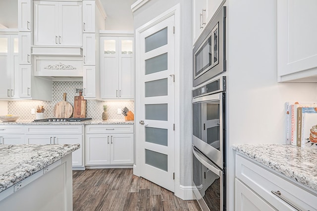 kitchen featuring appliances with stainless steel finishes, white cabinetry, dark wood finished floors, and tasteful backsplash