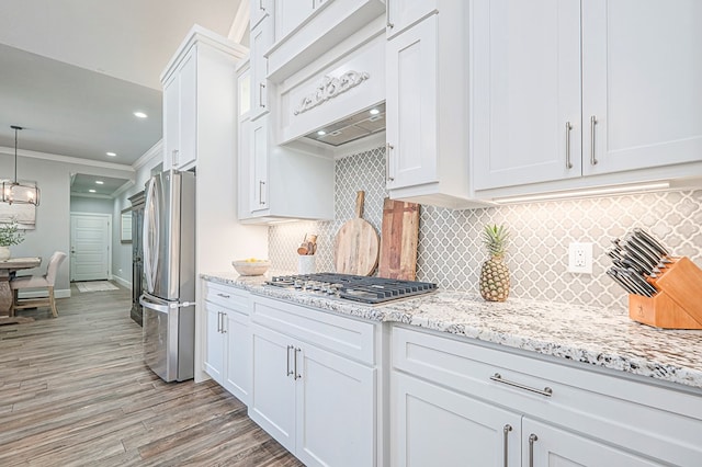 kitchen featuring stainless steel appliances, white cabinets, hanging light fixtures, and crown molding