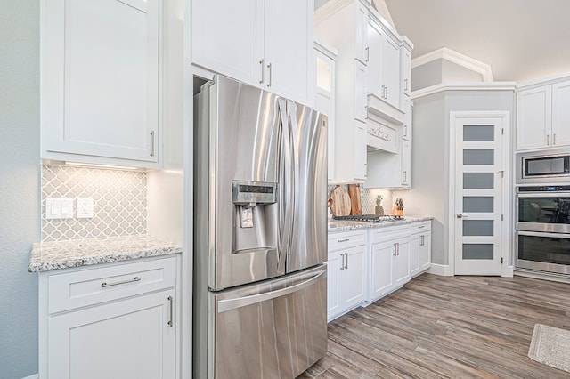 kitchen featuring stainless steel appliances, light stone counters, decorative backsplash, and white cabinets