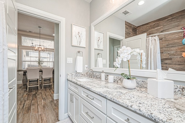 full bathroom with a notable chandelier, visible vents, a shower with shower curtain, vanity, and wood finished floors