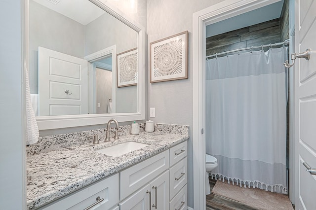 full bath with a textured wall, vanity, and toilet