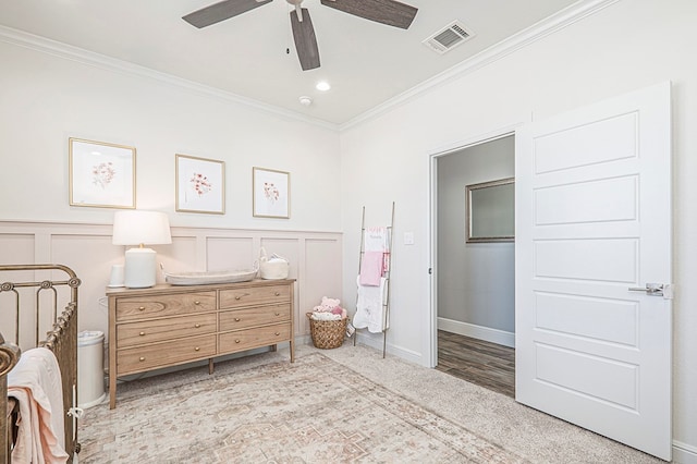 bedroom featuring wainscoting, visible vents, a decorative wall, and ornamental molding