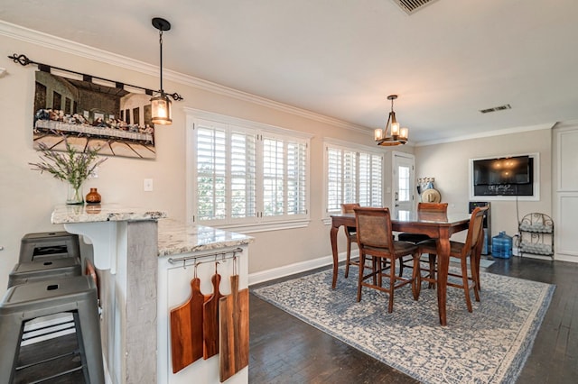 dining area with a chandelier, ornamental molding, and dark wood-type flooring