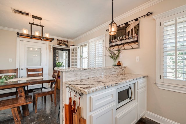 kitchen featuring kitchen peninsula, white cabinetry, hanging light fixtures, and ornamental molding