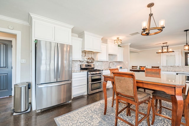 kitchen with dark hardwood / wood-style floors, white cabinetry, stainless steel appliances, and decorative light fixtures