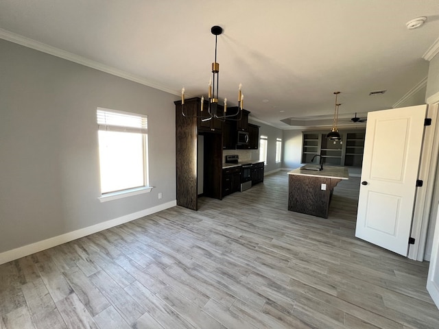 kitchen with crown molding, decorative light fixtures, appliances with stainless steel finishes, an island with sink, and a wealth of natural light