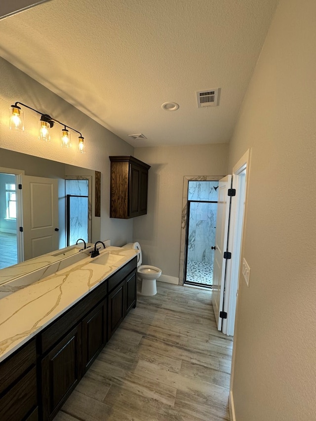 bathroom with vanity, hardwood / wood-style floors, a textured ceiling, and tiled shower