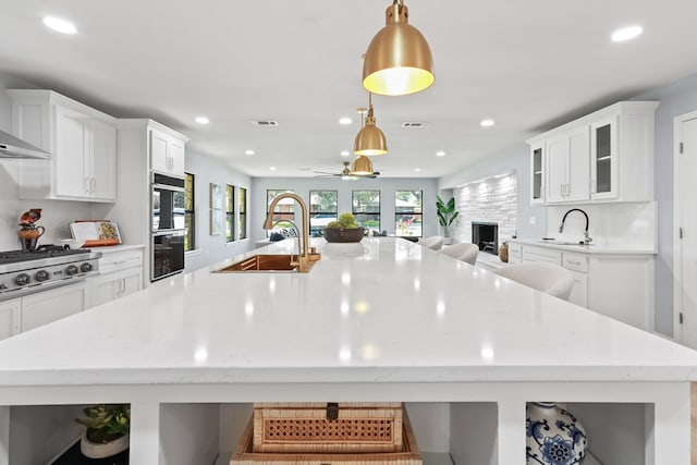 2208 Bedford Dr, Midland, TX 79701 - kitchen with a spacious island, open floor plan, stainless steel gas stovetop, white cabinets, and a sink