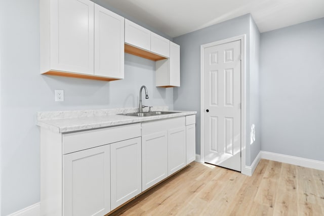 2208 Bedford Dr, Midland, TX 79701 - kitchen featuring white cabinetry, baseboards, light wood finished floors, and a sink