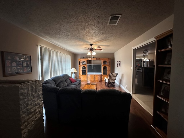 living room with hardwood / wood-style floors, a textured ceiling, and ceiling fan