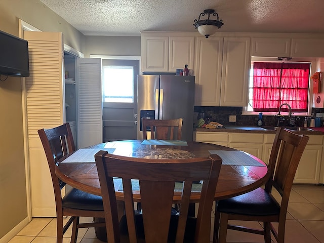 tiled dining area featuring sink and a textured ceiling