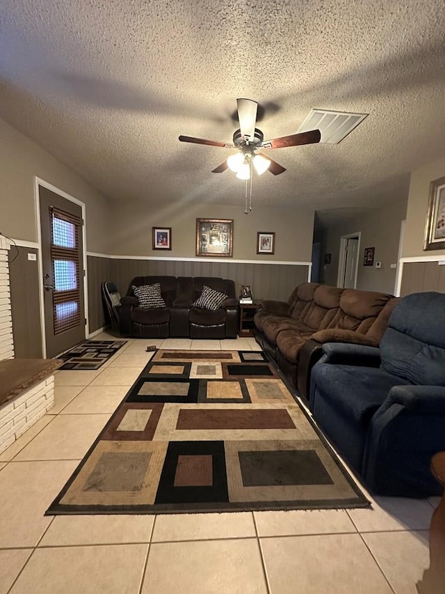 living room with ceiling fan, light tile patterned floors, and a textured ceiling