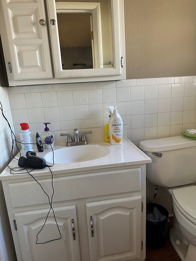 bathroom with vanity, tile walls, and toilet