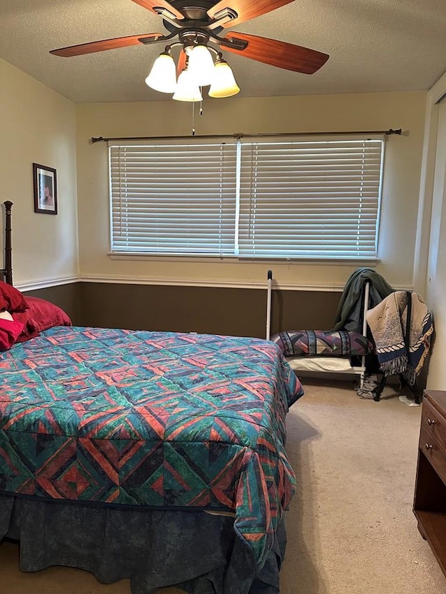 bedroom featuring ceiling fan, carpet, and a textured ceiling