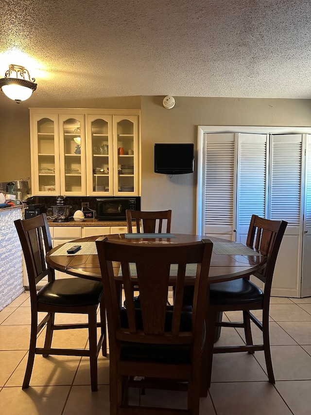 tiled dining room featuring a textured ceiling