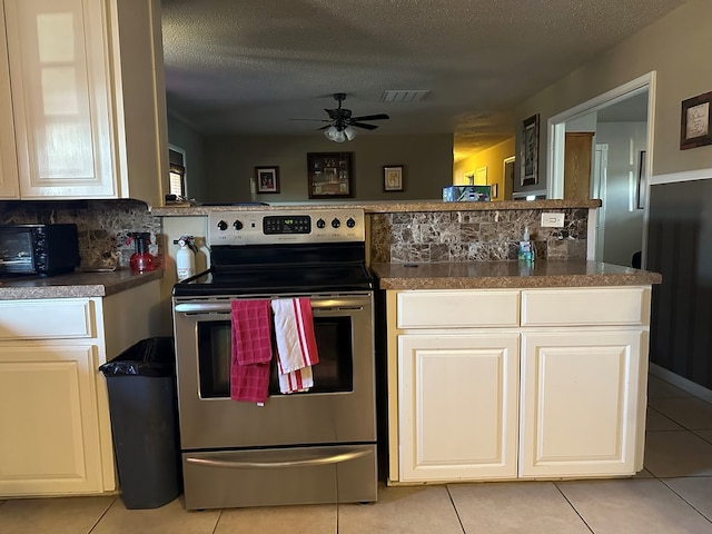 kitchen featuring backsplash, electric range, a textured ceiling, and light tile patterned flooring