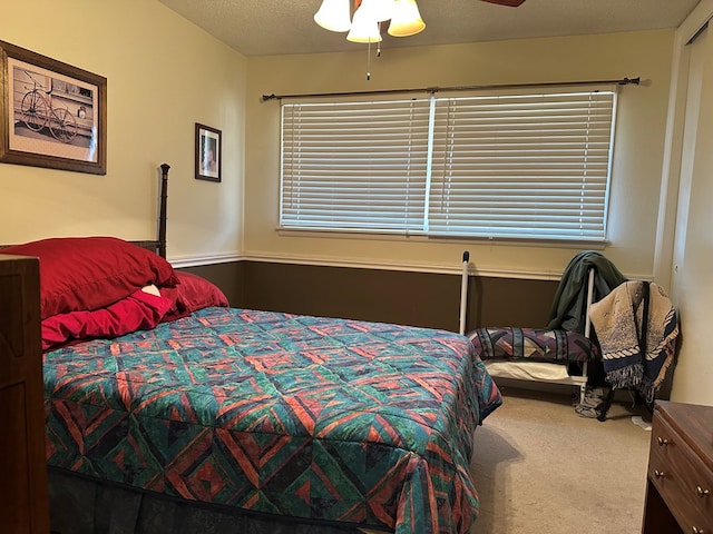 carpeted bedroom featuring ceiling fan and a textured ceiling