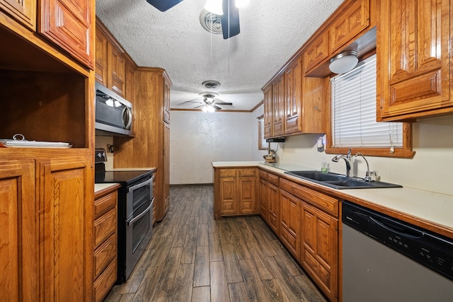 kitchen featuring appliances with stainless steel finishes, brown cabinetry, dark wood-type flooring, a ceiling fan, and a sink