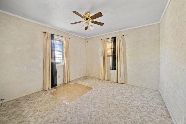 carpeted empty room with ceiling fan, baseboards, and crown molding