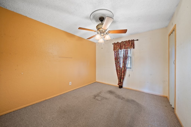 unfurnished room with carpet floors, a textured ceiling, baseboards, and a ceiling fan