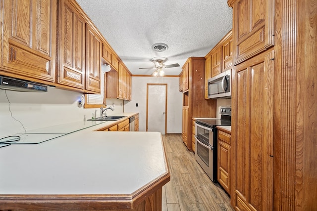 kitchen with visible vents, ceiling fan, appliances with stainless steel finishes, light wood-style floors, and a sink