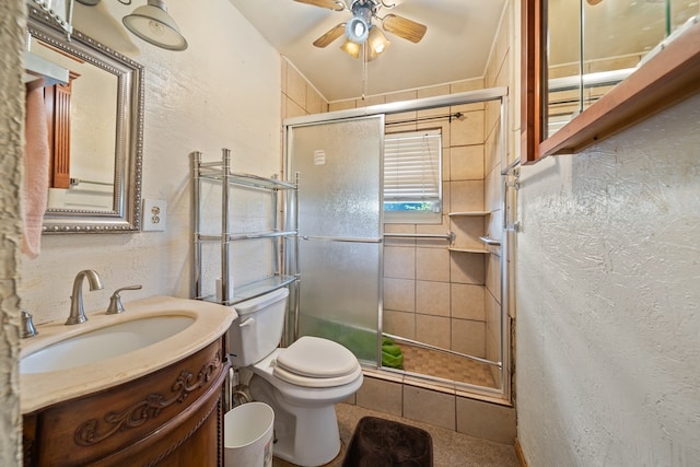 bathroom with a textured wall, a shower stall, toilet, and vanity