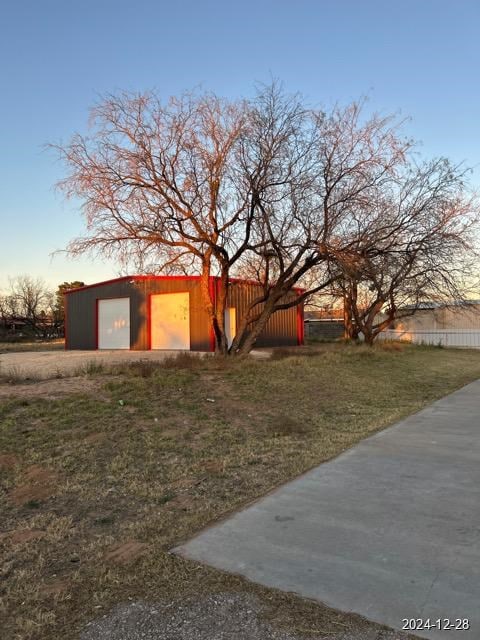 yard at dusk with a garage and an outbuilding