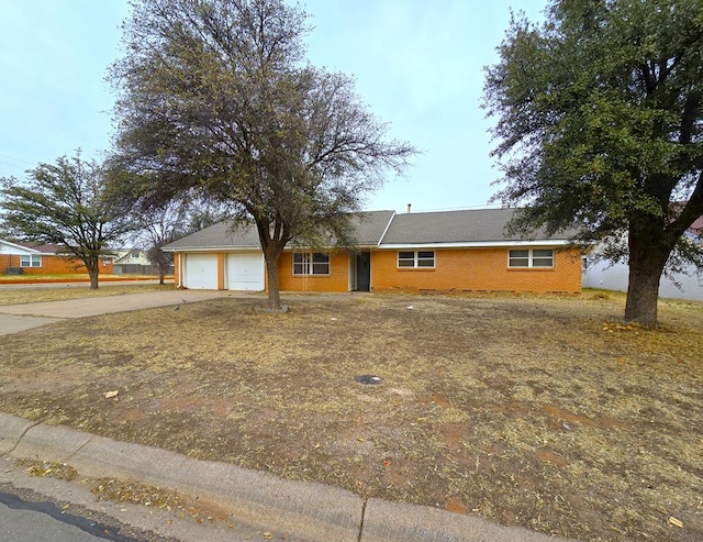 ranch-style home with concrete driveway, brick siding, and an attached garage