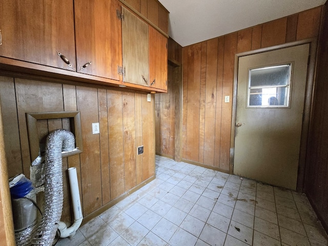 clothes washing area featuring cabinet space and wood walls