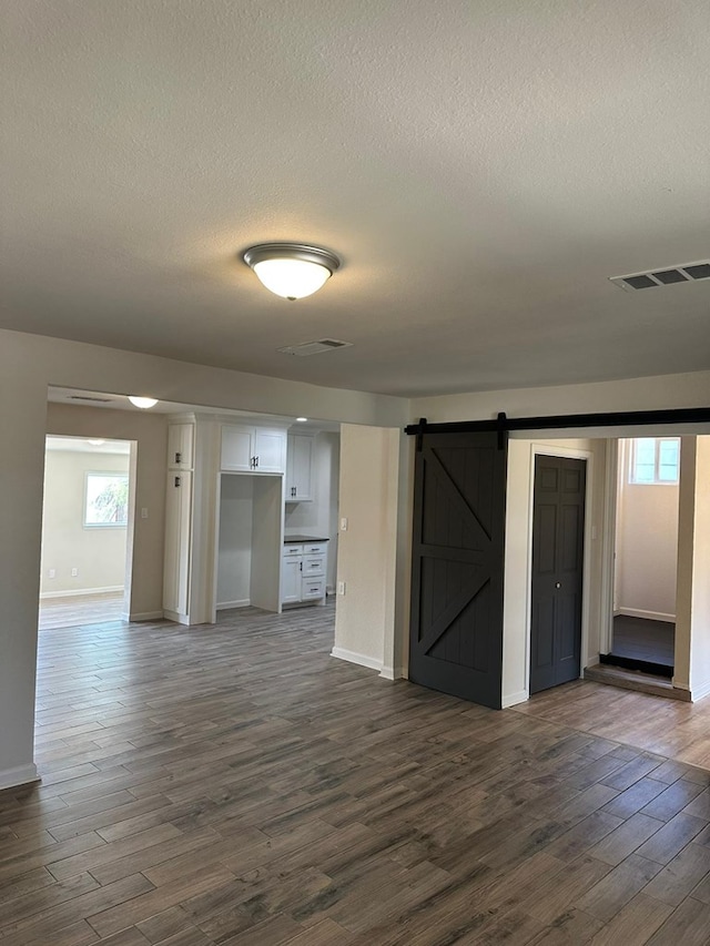 103 W Cowden Ave, Midland, TX 79701 - unfurnished room with a barn door, dark wood finished floors, a textured ceiling, and baseboards