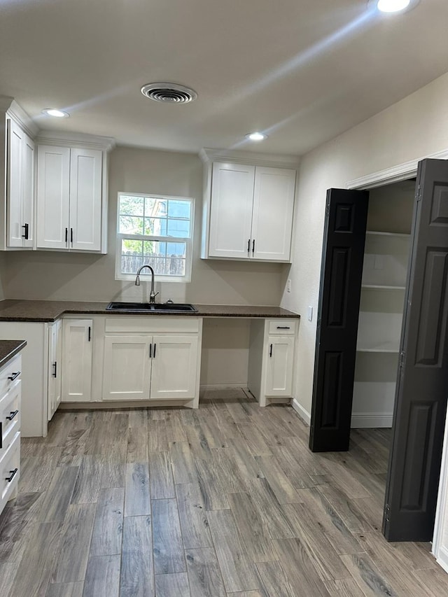 103 W Cowden Ave, Midland, TX 79701 - kitchen with a sink, dark countertops, light wood-style flooring, white cabinets, and recessed lighting