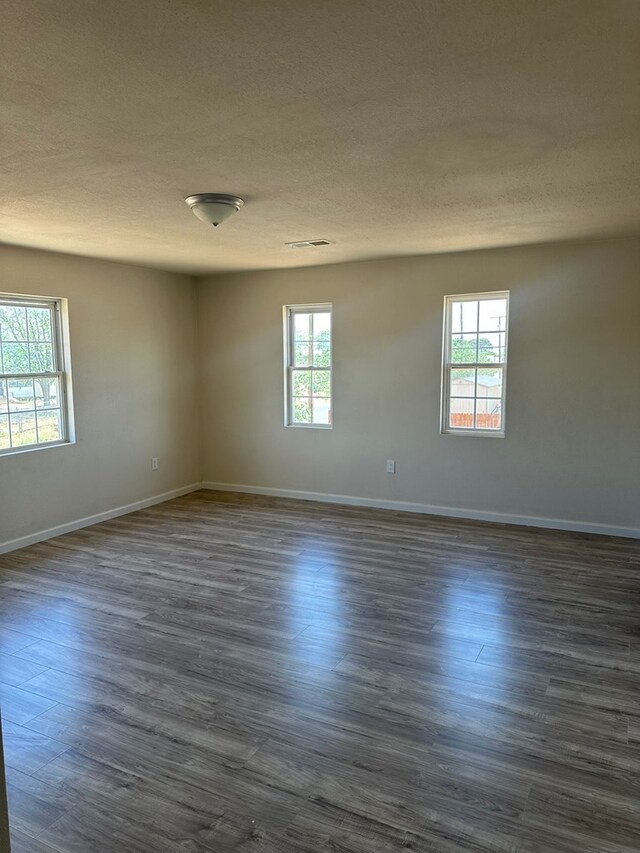 103 W Cowden Ave, Midland, TX 79701 - spare room featuring plenty of natural light, a textured ceiling, dark wood-style floors, and baseboards