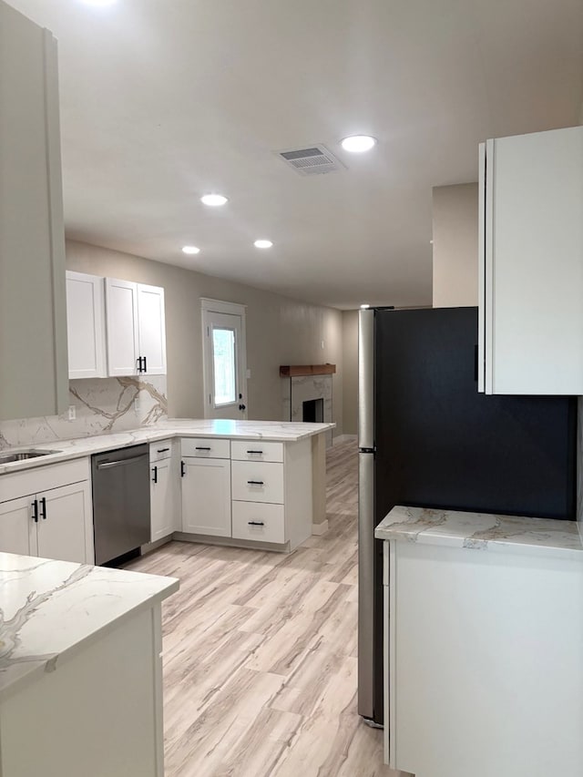 2612 Cimmaron Ave, Midland, TX 79705 - kitchen with stainless steel appliances, a peninsula, white cabinets, a fireplace, and recessed lighting