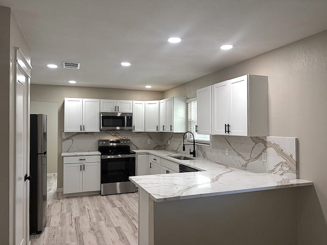 2612 Cimmaron Ave, Midland, TX 79705 - kitchen with stainless steel appliances, a peninsula, light stone counters, backsplash, and white cabinets