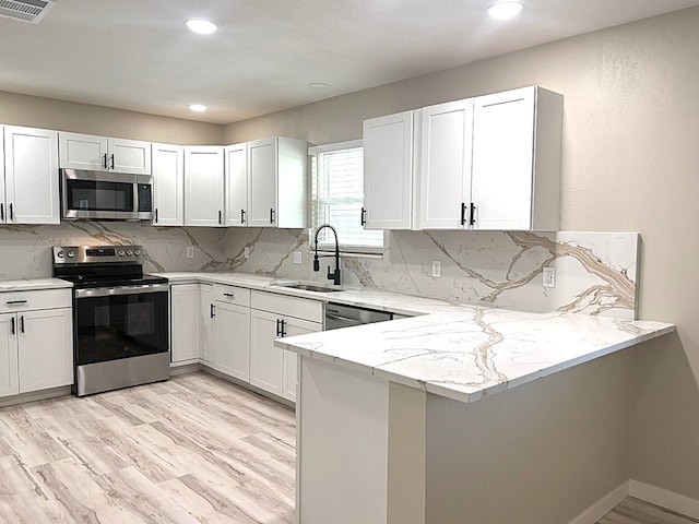 2612 Cimmaron Ave, Midland, TX 79705 - kitchen featuring appliances with stainless steel finishes, light stone countertops, light wood-type flooring, a peninsula, and recessed lighting