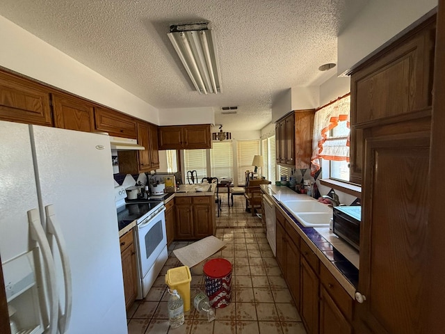 3804 Faircircle, Midland, TX 79707 - kitchen with white appliances, a textured ceiling, under cabinet range hood, light floors, and brown cabinets