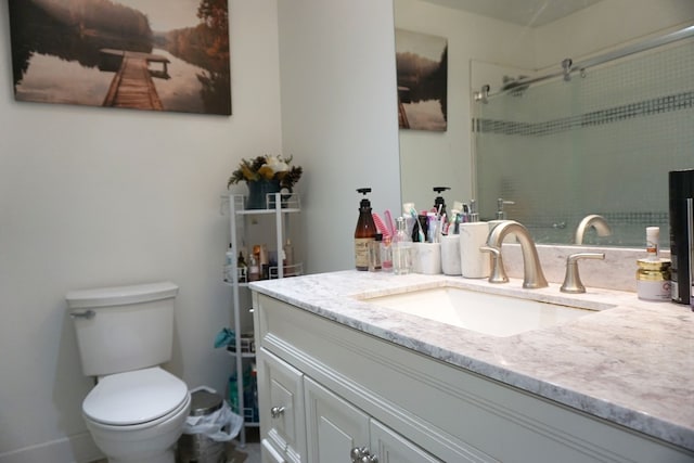 bathroom with a shower with door, vanity, and toilet