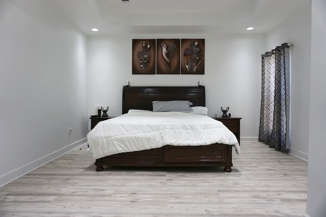 bedroom with a tray ceiling and light hardwood / wood-style flooring