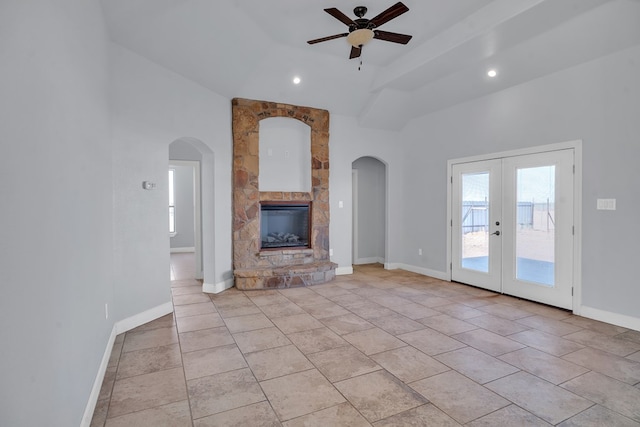 unfurnished living room with arched walkways, french doors, baseboards, and a ceiling fan