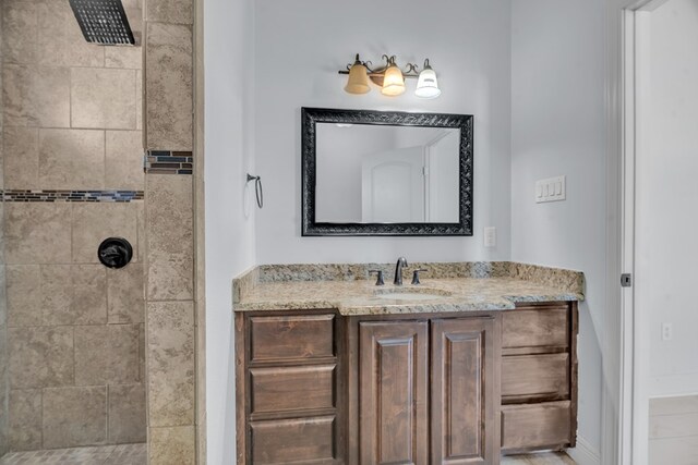 bathroom featuring tiled shower and vanity