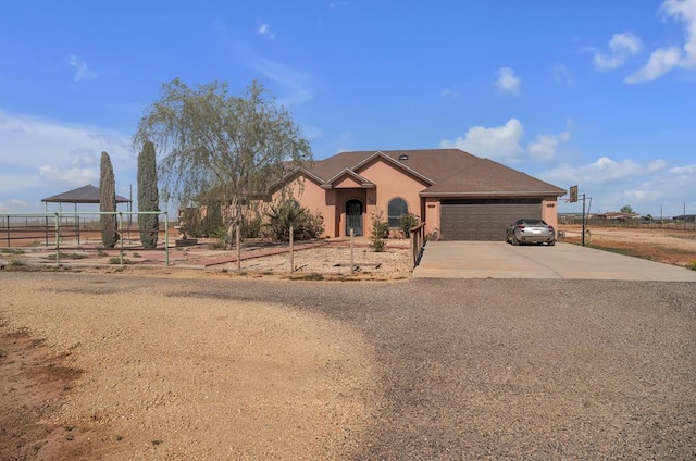 ranch-style home featuring fence, a garage, driveway, and stucco siding
