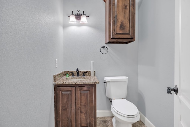 half bathroom featuring vanity, baseboards, and toilet