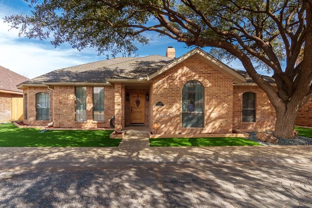 4902 Foxboro Ct, Midland, TX 79705 - ranch-style house with a chimney, brick siding, a front lawn, and roof with shingles