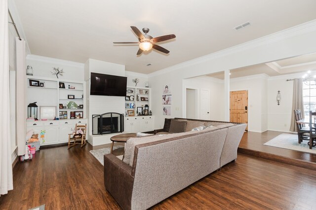 4902 Foxboro Ct, Midland, TX 79705 - living area with dark wood finished floors, a ceiling fan, a fireplace with raised hearth, crown molding, and built in features